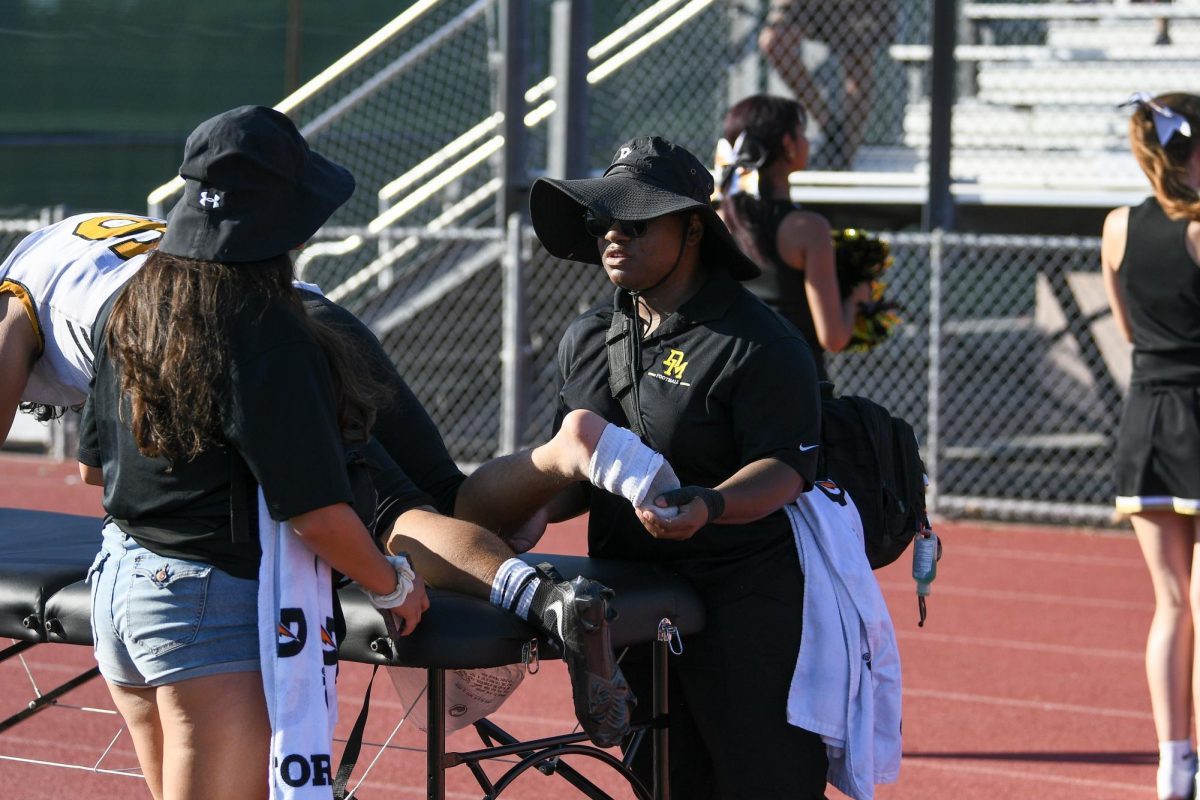Ms. Breya taping an ankle after player suffered sprained wrist